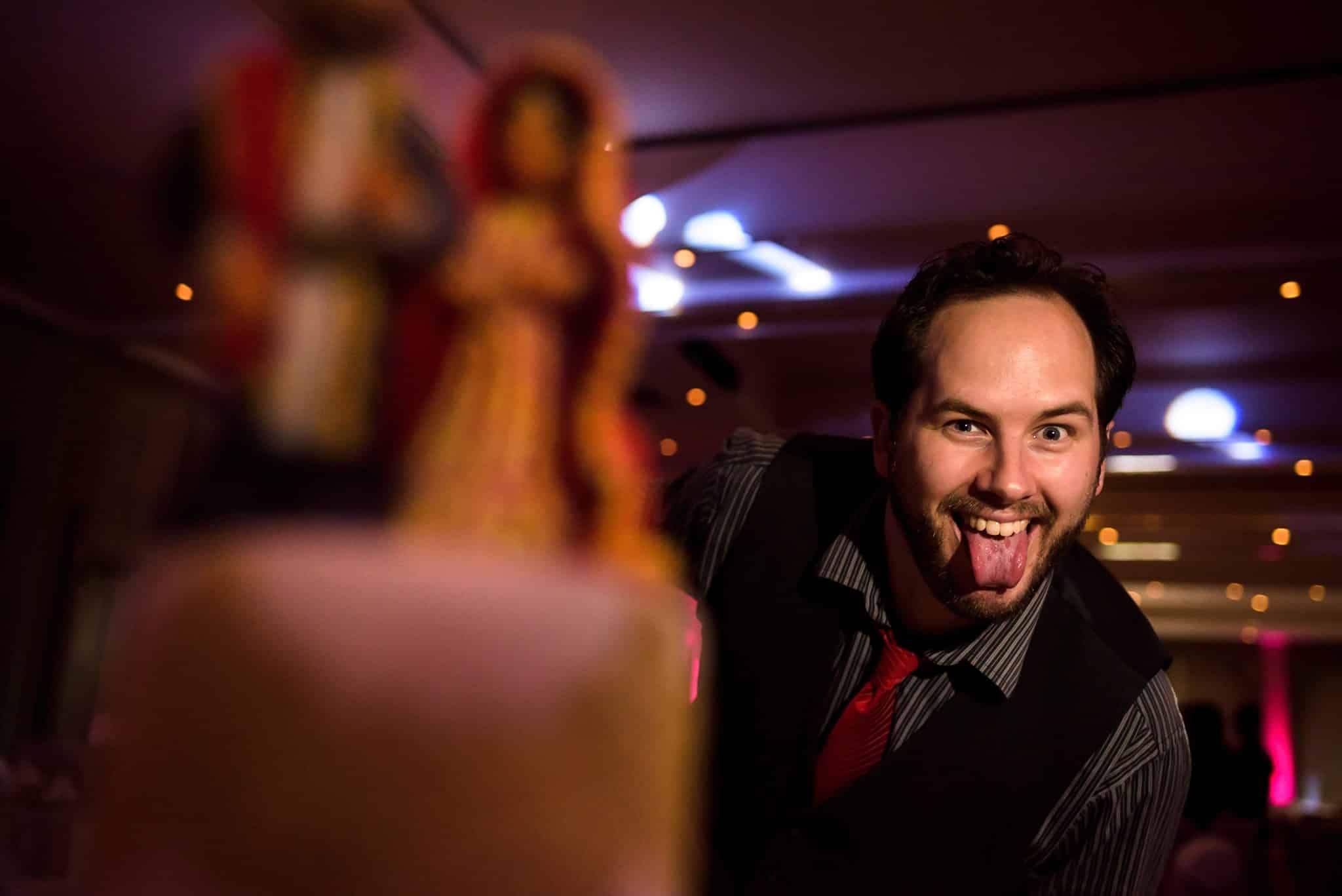 Wedding videographer Jon hiding behind wedding cake